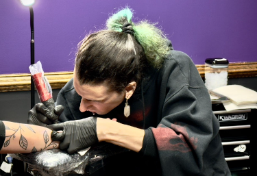 Moth tattooing someone's forearm.